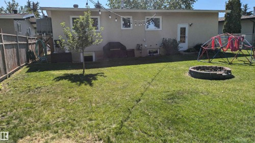 The property features a spacious backyard with a lawn and a fire pit - 4208 89 Street Nw, Edmonton, AB - Outdoor