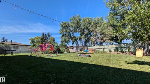 The property features an extensive backyard with a well-maintained lawn, mature trees, and a privacy fence - 4208 89 Street Nw, Edmonton, AB - Outdoor