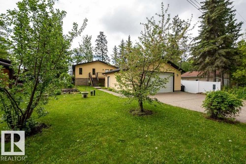 Spacious property featuring a detached garage with a white panel door, a paved driveway, and established landscaping - 90 2001 Twp Rd, Rural Leduc County, AB 
