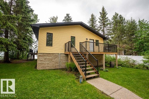 Exterior featuring yellow siding, a black roofline, and a stone-finish foundation - 90 2001 Twp Rd, Rural Leduc County, AB 