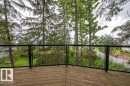 Outdoor deck featuring wood-finish flooring and a glass panel railing - 90 2001 Twp Rd, Rural Leduc County, AB 
