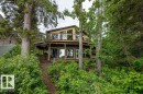 Multi-level residence featuring a wrap-around deck with glass railings and wood flooring - 90 2001 Twp Rd, Rural Leduc County, AB 