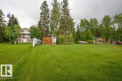 Expansive green lawn with mature trees and a two-story residence featuring multiple balconies - 90 2001 Twp Rd, Rural Leduc County, AB 