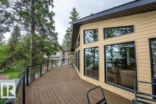 Expansive outdoor deck featuring wood-finish flooring and glass panel railing - 90 2001 Twp Rd, Rural Leduc County, AB 
