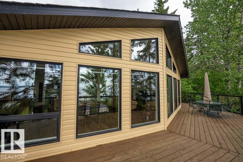 Expansive wood deck with black metal and glass panel railing - 90 2001 Twp Rd, Rural Leduc County, AB 