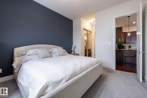 A comfortable room with a neutral-colored bed frame and a dark accent wall - 454 6079 Maynard Way, Edmonton, AB - Indoor Photo Showing Bedroom