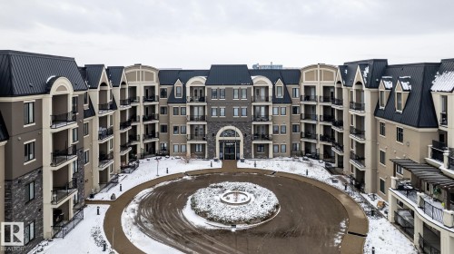 The property features a large circular driveway with a central garden area - 454 6079 Maynard Way, Edmonton, AB - Outdoor With Facade