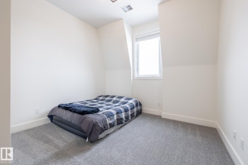 The room features light gray carpeting, white walls, and a window providing natural light - 454 6079 Maynard Way, Edmonton, AB - Indoor Photo Showing Bedroom