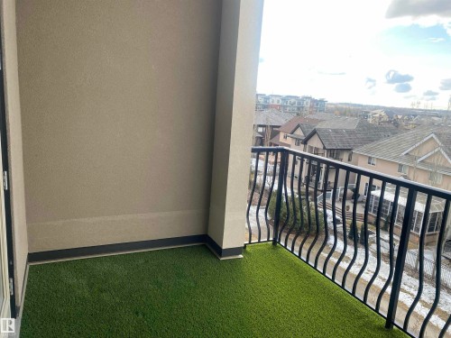 The property features a balcony with a synthetic turf floor and a black metal railing - 454 6079 Maynard Way, Edmonton, AB - Outdoor