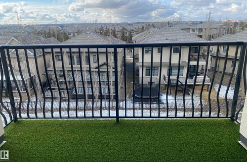 The property features a balcony with artificial turf flooring and a black metal railing, offering expansive views of the surrounding residential neighborhood - 454 6079 Maynard Way, Edmonton, AB - Outdoor With View