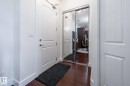 Entryway featuring dark hardwood flooring, a white paneled door, and a mirrored closet with sliding doors - 454 6079 Maynard Way, Edmonton, AB  - Indoor Photo Showing Other Room 