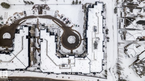 Aerial view of the property and surrounding neighborhood, featuring a large circular drive and parking areas - 454 6079 Maynard Way, Edmonton, AB - 