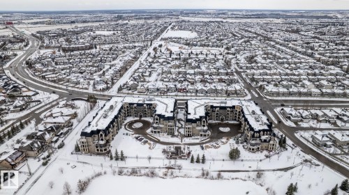 Aerial view showcasing the property's distinct architectural style, surrounded by a residential neighborhood with snow-covered rooftops - 454 6079 Maynard Way, Edmonton, AB - Outdoor With View