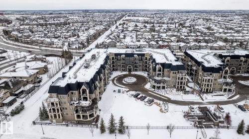 Aerial view of the property, showcasing its distinctive architectural style with dark sloped roofs and light-colored facades - 454 6079 Maynard Way, Edmonton, AB - Outdoor With View