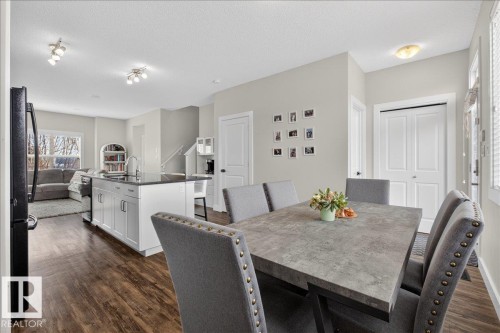Open concept living area with hardwood flooring, a kitchen island with a dark countertop, and views of the living room - 9034 Rosenthal Link Link, Edmonton, AB - Indoor Photo Showing Dining Room