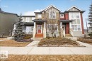 The property features a stone facade and a red front door, complemented by a front porch with white railings - 9034 Rosenthal Link Link, Edmonton, AB  - Outdoor With Facade 