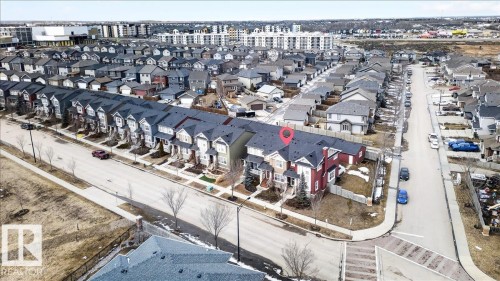 This aerial view showcases a property with a distinct red exterior, situated at a corner location within a row of townhomes - 9034 Rosenthal Link Link, Edmonton, AB - Outdoor With View