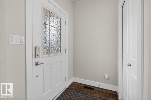 Entryway featuring a white door with decorative glass, a modern smart lock, and hardwood flooring - 9034 Rosenthal Link Link, Edmonton, AB - Indoor Photo Showing Other Room