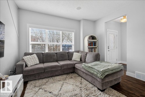 Living room with bright white walls, dark wood flooring, and a large window with white blinds - 9034 Rosenthal Link Link, Edmonton, AB - Indoor Photo Showing Living Room