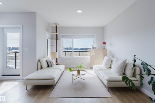 Living area featuring light-toned flooring, a large window providing natural light, and a glass-paneled door - 1129 Keswick Drive, Edmonton, AB - Indoor Photo Showing Living Room