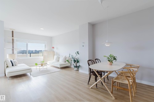This open-concept living and dining area features light-toned flooring throughout, large windows providing natural light, and a modern ceiling light fixture over the dining space - 1129 Keswick Drive, Edmonton, AB - Indoor