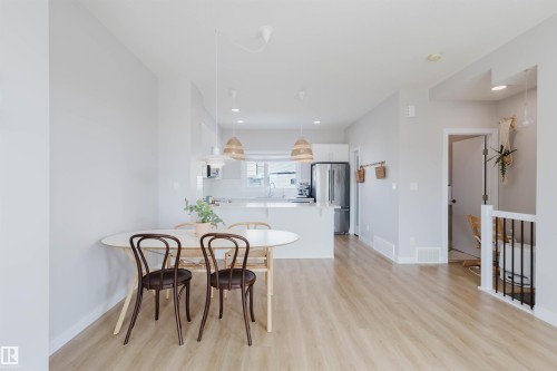 The property features an open-concept living area with light wood-style flooring throughout - 1129 Keswick Drive, Edmonton, AB - Indoor Photo Showing Dining Room