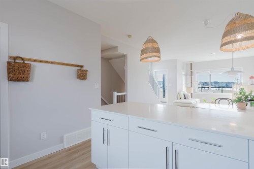 The kitchen features an island with white cabinetry and chrome hardware, and two woven pendant lights - 1129 Keswick Drive, Edmonton, AB - Indoor