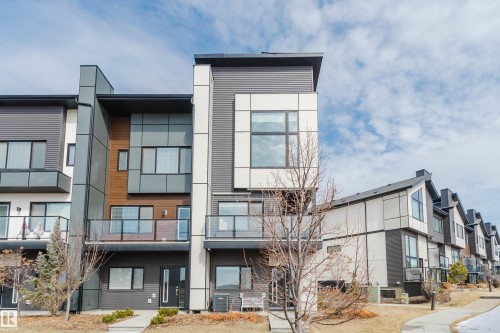 The property features a contemporary architectural style with a multi-toned exterior, including dark siding, light panels, and wood-toned accents - 1129 Keswick Drive, Edmonton, AB - Outdoor With Balcony With Facade