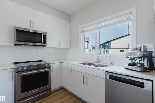 The kitchen features white cabinetry, white countertops, and a white subway tile backsplash - 1129 Keswick Drive, Edmonton, AB - Indoor Photo Showing Kitchen With Stainless Steel Kitchen With Double Sink