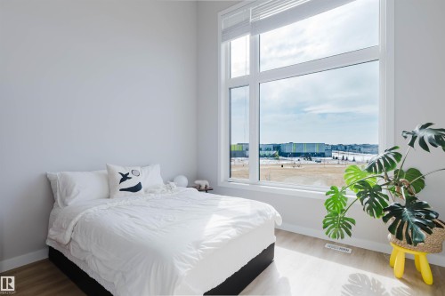This room features a large window with white frames, providing expansive views and natural light - 1129 Keswick Drive, Edmonton, AB - Indoor Photo Showing Bedroom