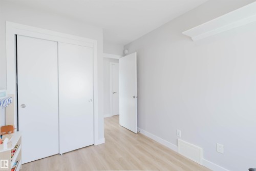 The room features light-toned walls and flooring, with white sliding closet doors and white trim - 1129 Keswick Drive, Edmonton, AB - Indoor Photo Showing Other Room