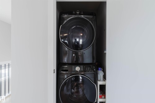 Integrated laundry area featuring a stacked washer and dryer unit - 1129 Keswick Drive, Edmonton, AB - Indoor Photo Showing Laundry Room