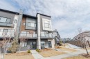 Contemporary townhome with a modern facade featuring various siding materials, prominent balconies with glass railings, and a concrete pathway leading to the entrance - 1129 Keswick Drive, Edmonton, AB  - Outdoor 
