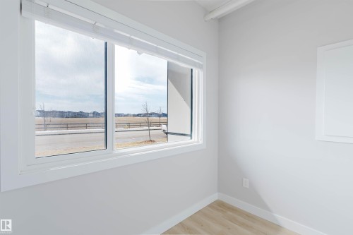 A bright room featuring light-colored walls, a large window, and light wood flooring - 1129 Keswick Drive, Edmonton, AB - Indoor Photo Showing Other Room