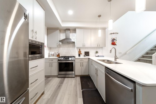 The kitchen features light-colored cabinetry, stainless steel appliances including a refrigerator, microwave, and dishwasher, and a double basin sink - 22931 96 Avenue, Edmonton, AB - Indoor Photo Showing Kitchen With Double Sink With Upgraded Kitchen