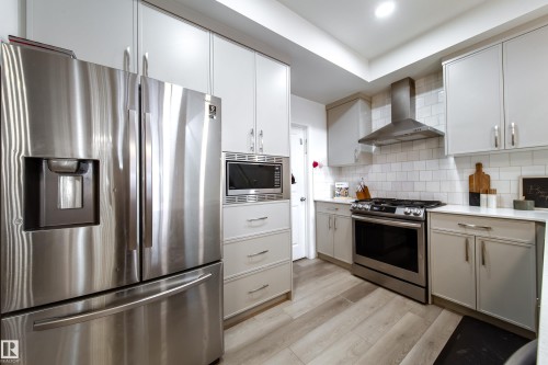 The kitchen features stainless steel appliances, including a refrigerator, microwave, and range with a range hood - 22931 96 Avenue, Edmonton, AB - Indoor Photo Showing Kitchen With Upgraded Kitchen