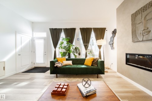 Living area featuring light-toned flooring, a fireplace integrated into a textured wall, and a full-light entry door - 22931 96 Avenue, Edmonton, AB - Indoor With Fireplace