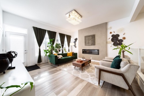 Living area featuring light wood flooring, a fireplace, and a decorative light fixture - 22931 96 Avenue, Edmonton, AB - Indoor Photo Showing Living Room With Fireplace