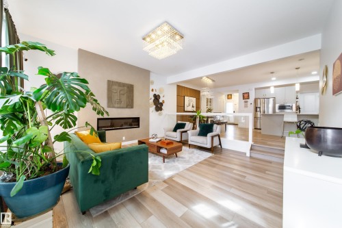 The living area features light-toned flooring, a linear fireplace, and a decorative chandelier - 22931 96 Avenue, Edmonton, AB - Indoor Photo Showing Living Room With Fireplace