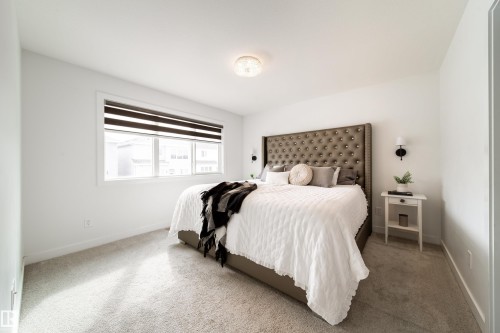 This room features light-colored carpeting, a window with blinds, and a bed with a tufted headboard - 22931 96 Avenue, Edmonton, AB - Indoor Photo Showing Bedroom