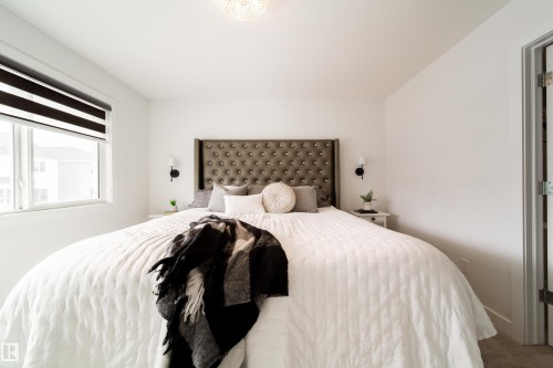 Bright bedroom featuring a large window with horizontal blinds, a tufted headboard, and wall-mounted sconces - 22931 96 Avenue, Edmonton, AB - Indoor Photo Showing Bedroom