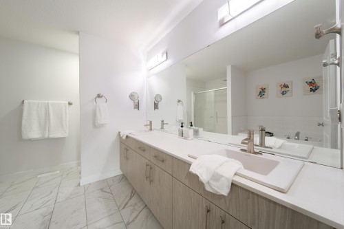 The bathroom features a dual vanity with light wood cabinetry, a large mirror, and a shower with a sliding glass door - 22931 96 Avenue, Edmonton, AB - Indoor Photo Showing Bathroom