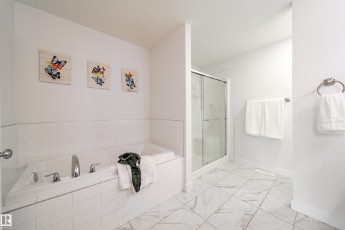 The bathroom features a built-in bathtub with white subway tile surround, a separate shower with a clear glass enclosure, and white tiled flooring - 22931 96 Avenue, Edmonton, AB - Indoor Photo Showing Bathroom
