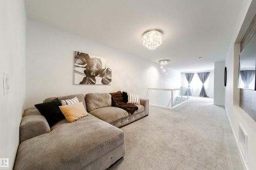 This inviting living area features soft carpet flooring, a crystal chandelier, and ample wall space - 22931 96 Avenue, Edmonton, AB - Indoor Photo Showing Living Room