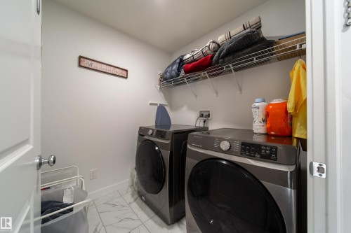 Dedicated laundry room featuring light-colored walls, tile flooring, and overhead wire shelving - 22931 96 Avenue, Edmonton, AB - Indoor Photo Showing Laundry Room