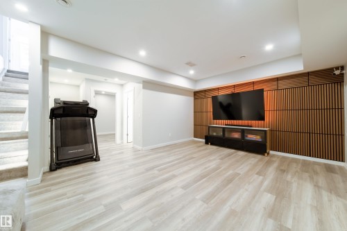 Spacious lower level featuring light-toned flooring, recessed lighting, and a striking accent wall with wooden panels - 22931 96 Avenue, Edmonton, AB - Indoor