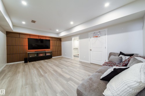 This entertainment area features light-colored flooring, recessed lighting, and a distinctive wood slat accent wall - 22931 96 Avenue, Edmonton, AB - Indoor