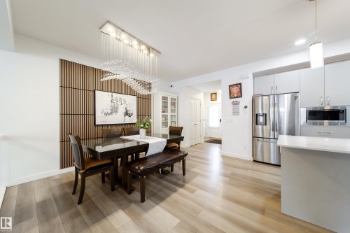 The dining area features a stylish chandelier and a slatted accent wall, complementing the light-toned flooring - 22931 96 Avenue, Edmonton, AB - Indoor