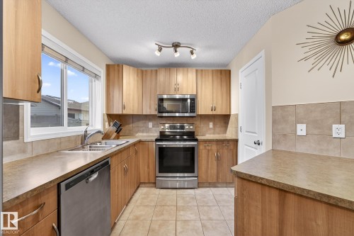 The kitchen features wood cabinetry, stainless steel appliances, and a window above the sink providing natural light - 219 60 Street, Edmonton, AB - Indoor Photo Showing Kitchen With Double Sink