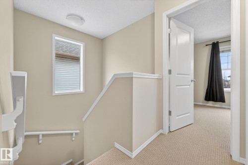 The property features carpeted stairs and hallways, neutral wall paint, and white trim - 219 60 Street, Edmonton, AB - Indoor Photo Showing Other Room